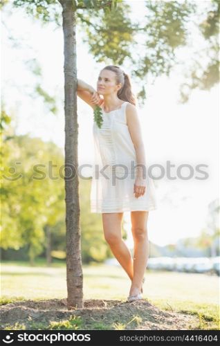 Portrait of thoughtful young woman standing near seedling tree