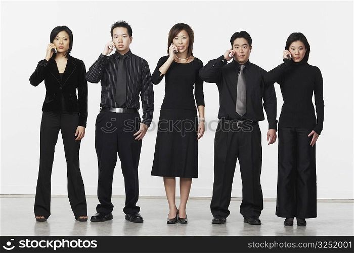 Portrait of three businesswomen and two businessmen using mobile phones