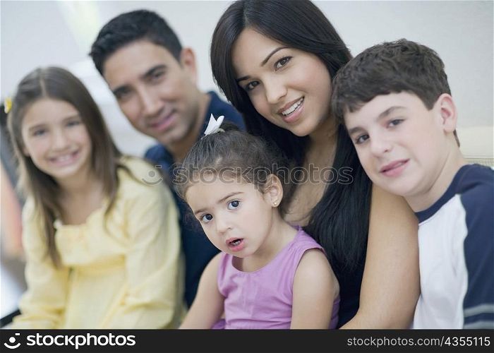Portrait of three children sitting together with their parents