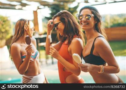 Portrait of three female friends eating icecream by pool in summer