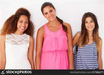 Portrait Of Three Female Friends Leaning Against Wall