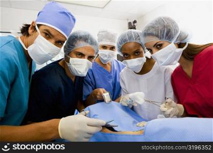Portrait of three female surgeons and two male surgeons operating a patient