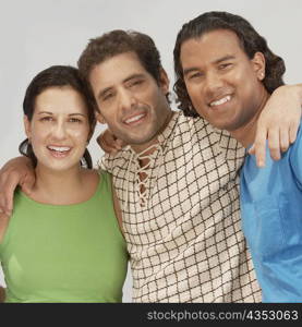 Portrait of three friends standing with their arms around each other and smiling