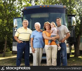 Portrait of three generation Caucasian family standing in front of recreational vehicle smiling and looking at viewer.