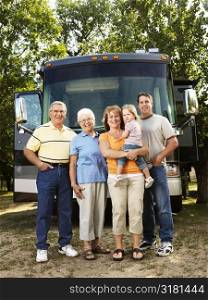 Portrait of three generation Caucasian family standing in front of recreational vehicle smiling and looking at viewer.