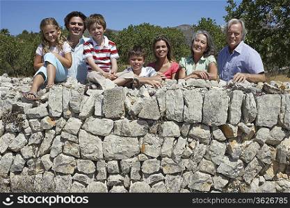 Portrait of three-generation family with three children (6-11) by stone wall