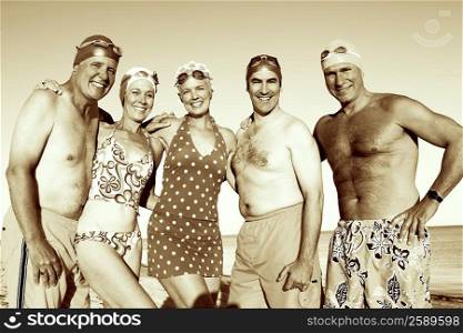 Portrait of three mature men and two mature women standing side by side on the beach and smiling
