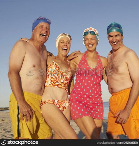 Portrait of three mature men and two mature women standing side by side on the beach and smiling