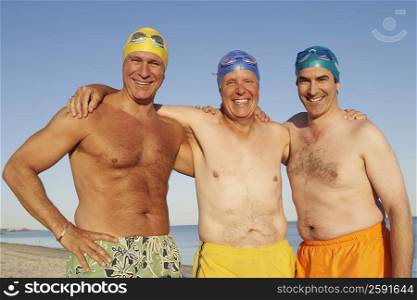 Portrait of three mature men standing side by side on the beach and smiling