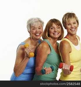 Portrait of three mature women holding dumbbells and smiling