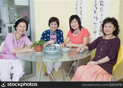 Portrait of three senior women and a mature woman sitting at a table