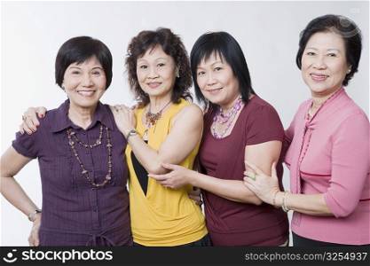 Portrait of three senior women and a mature woman standing together and smiling