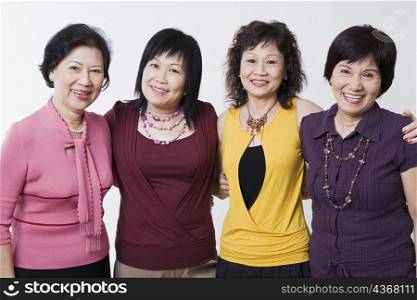 Portrait of three senior women and a mature woman standing together and smiling