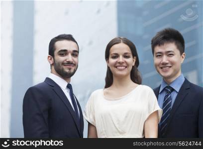 Portrait of three smiling business people, outdoors, business district