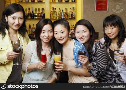 Portrait of three teenage girls and two young women holding drinks