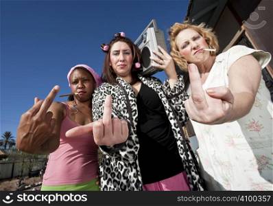 Portrait of three trashy women outdoors making a rude hand gesture