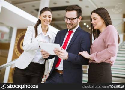 Portrait of three young businesspeople using digital tablet while colleague in office