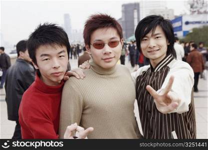 Portrait of three young men showing the peace sign