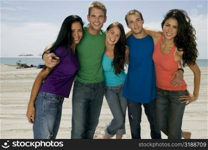 Portrait of three young women and two young men standing on the beach