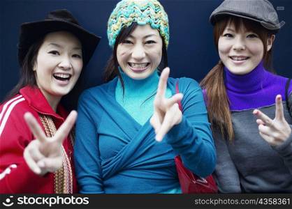 Portrait of three young women making the peace sign
