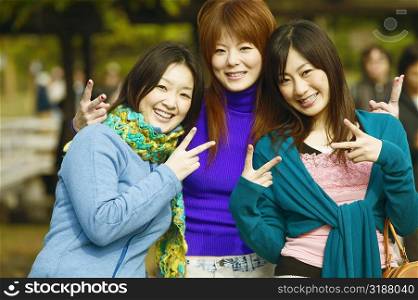 Portrait of three young women showing the peace sign