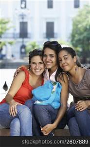 Portrait of three young women sitting and smiling