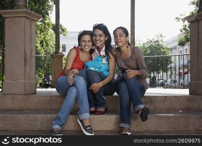 Portrait of three young women sitting and smiling