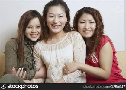 Portrait of three young women sitting together smiling
