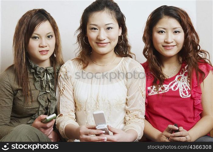 Portrait of three young women sitting together smiling