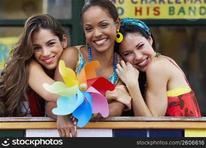 Portrait of three young women smiling and holding a pinwheel
