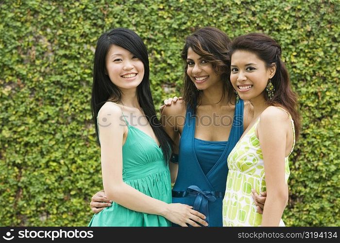 Portrait of three young women smiling with arms around each other