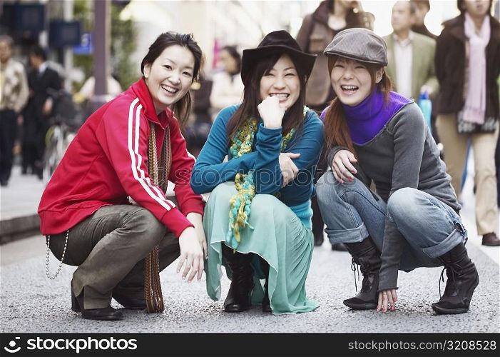 Portrait of three young women squatting on the street