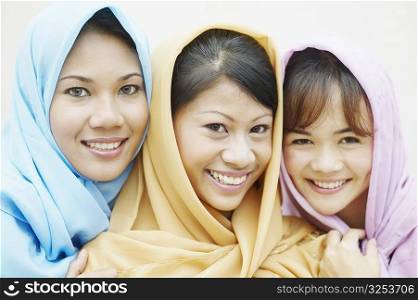 Portrait of three young women wearing scarves smiling