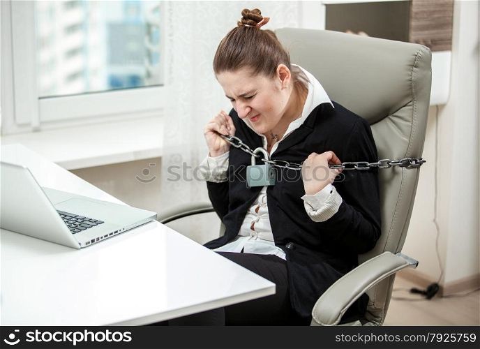 Portrait of tied businesswoman tearing apart metal chained