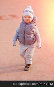 Portrait of toddler child in warm vest jacket outdoors. One year old baby boy wearing vest jacket at playground during sunset.