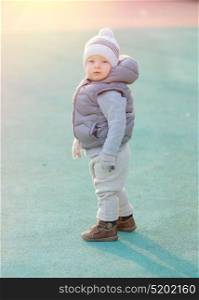 Portrait of toddler child in warm vest jacket outdoors. One year old baby boy wearing vest jacket at playground during sunset.