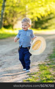 Portrait of toddler child outdoors. Rural scene with one year old baby boy with straw hat