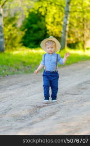 Portrait of toddler child outdoors. Rural scene with one year old baby boy wearing straw hat