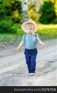Portrait of toddler child outdoors. Rural scene with one year old baby boy wearing straw hat