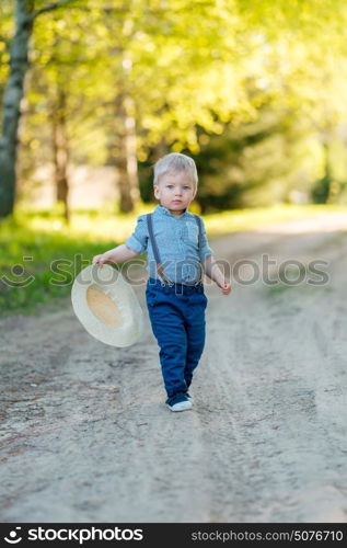 Portrait of toddler child outdoors. Rural scene with one year old baby boy with straw hat