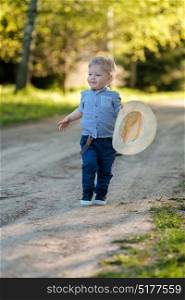 Portrait of toddler child outdoors. Rural scene with one year old baby boy with straw hat