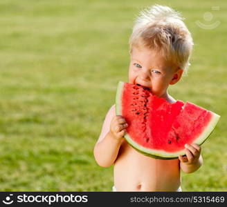 Portrait of toddler child outdoors. Rural scene with one year old baby boy eating watermelon slice in the garden. Dirty messy face of happy kid.