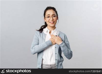 Portrait of touched, flattered young woman, teacher or office worker in glasses, hold hands on heart impressed with ncie gesture of coworker, smiling and sighing, look thankful and pleased.. Portrait of touched, flattered young woman, teacher or office worker in glasses, hold hands on heart impressed with ncie gesture of coworker, smiling and sighing, look thankful and pleased