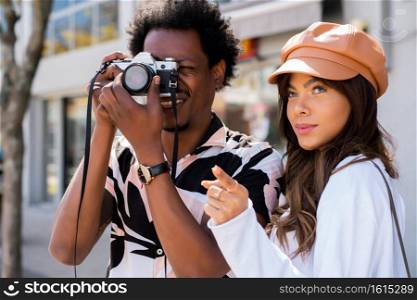 Portrait of tourist young couple using camera and taking photographs in the city. Tourism concept. 