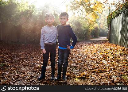 Portrait of twin boys, outdoors, surrounded by autumn leaves