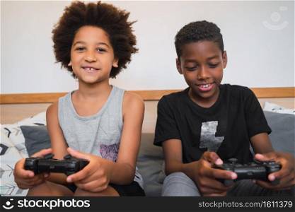 Portrait of two Afro American brothers playing video games at home. Lifestyle and technology concept.. Two brothers playing video games at home.