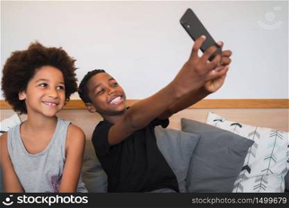 Portrait of two Afro American brothers taking a selfie with mobile phone at home. Lifestyle and technology concept.