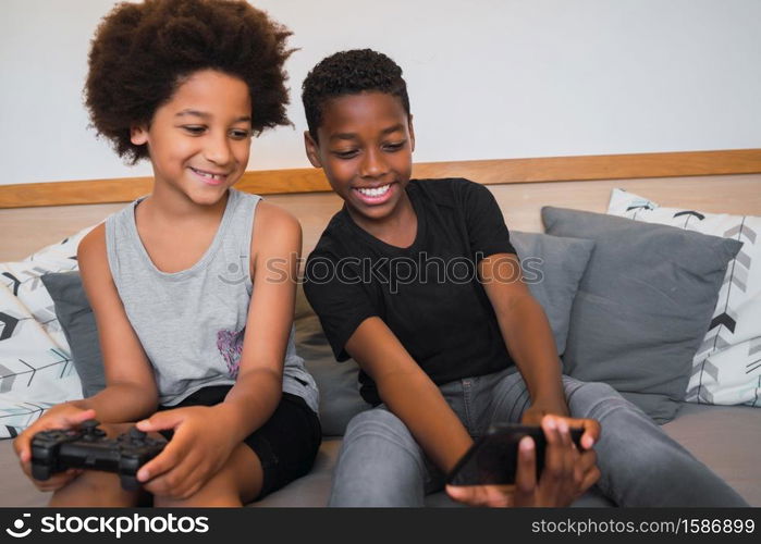 Portrait of two Afro American brothers taking a selfie with mobile phone at home. Lifestyle and technology concept.