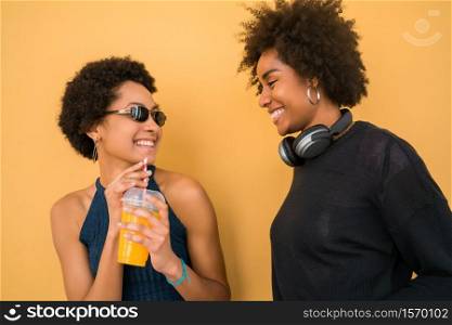 Portrait of two Afro friends having fun together and enjoying good time while drinking fresh fruit juice. Friendship and lifestyle concept.