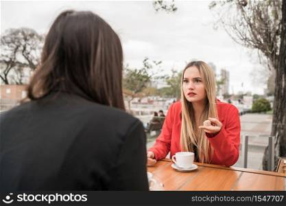 Portrait of two angry friends having a serious conversation and discussing while sitting at coffee shop. Friendship concept.